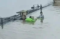 Η στιγμή που άνδρας, με το νερό ως το λαιμό, κουβαλά δύο παιδιά πάνω σε στρώμα