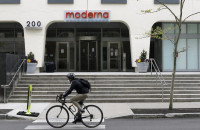 A bicyclists pedals past an entrance to a Moderna, Inc., building, Monday, May 18, 2020, in Cambridge, Mass. Moderna announced Monday that an experimental vaccine against the coronavirus showed encouraging results in very early testing, triggering hoped-f
