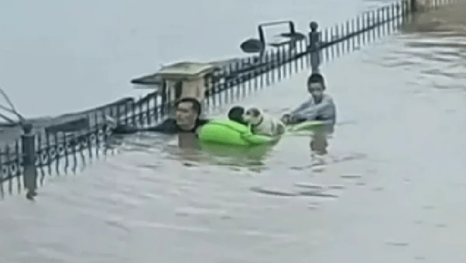 Η στιγμή που άνδρας, με το νερό ως το λαιμό, κουβαλά δύο παιδιά πάνω σε στρώμα